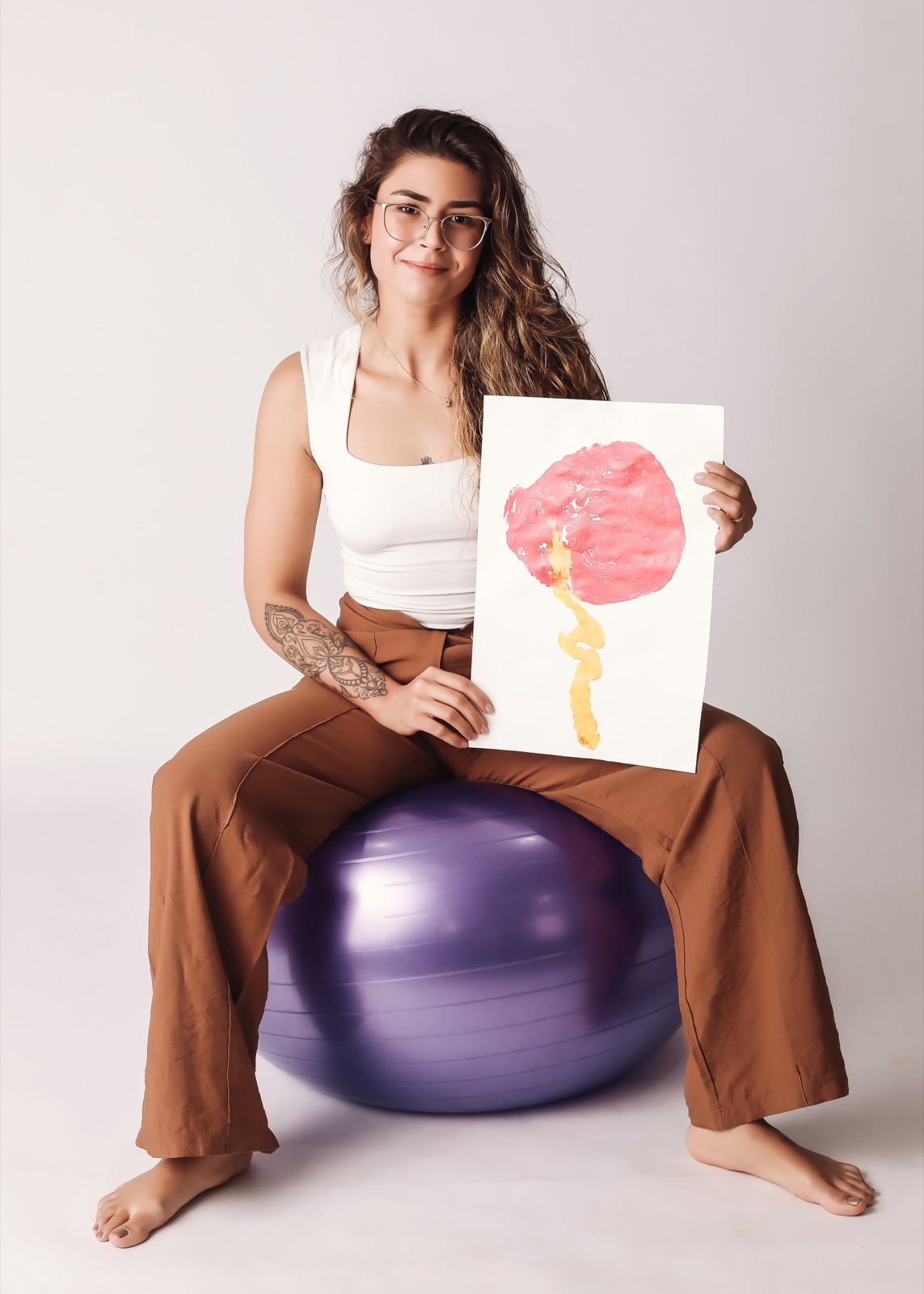 Brenda com materiais de doulagem, sentada na bola de parto